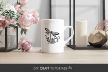 Load image into Gallery viewer, White mug with a black butterfly design on a wooden surface with flowers and decor.